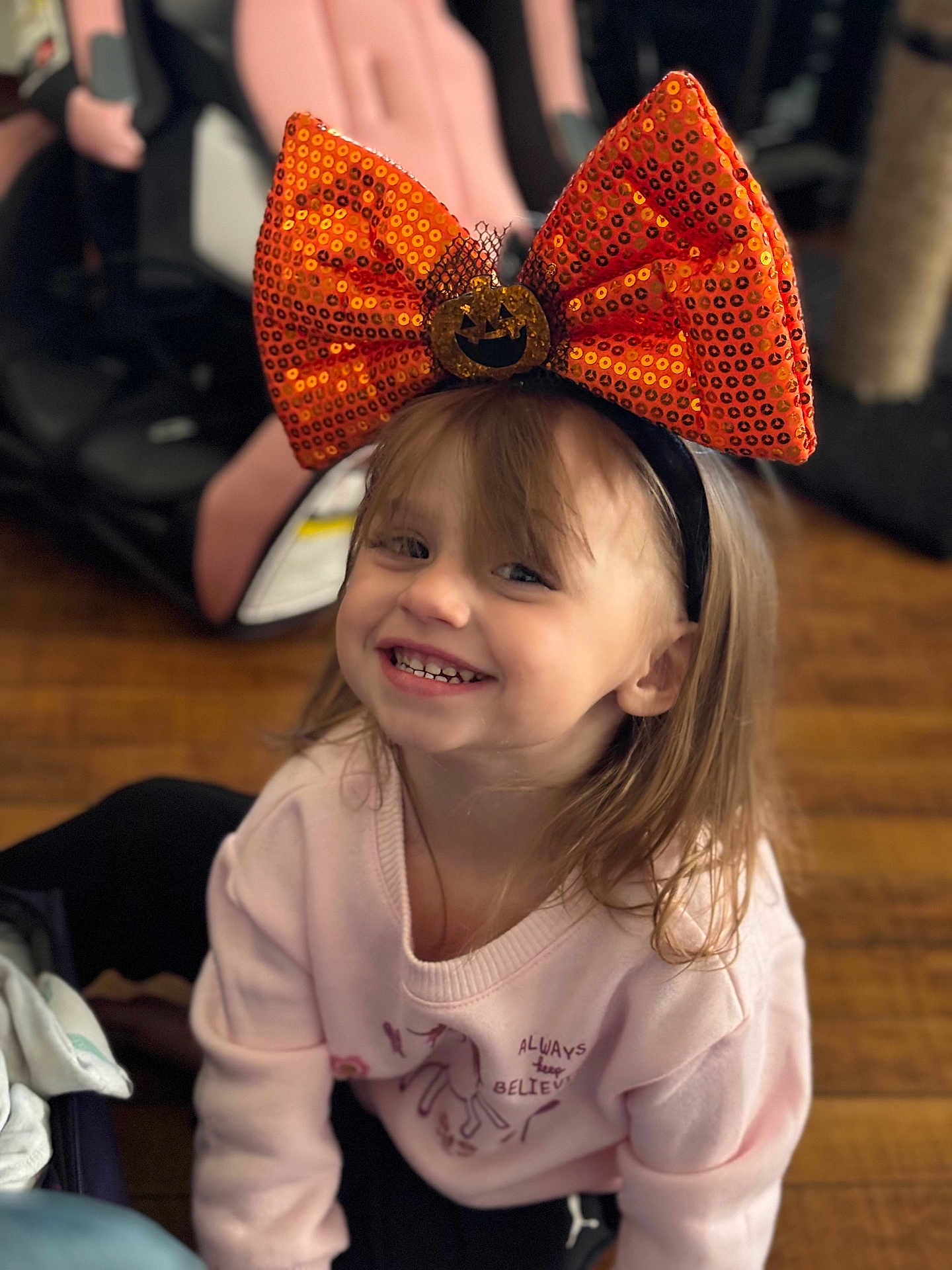 Lilianna joined the competition — help win amazing prizes! child, smile, happy, bow, headband, orange, pumpkin, halloween, indoor, floor, wooden_floor, clothing, pink_sweater, long_hair, person, cute, young, face, portrait, casual