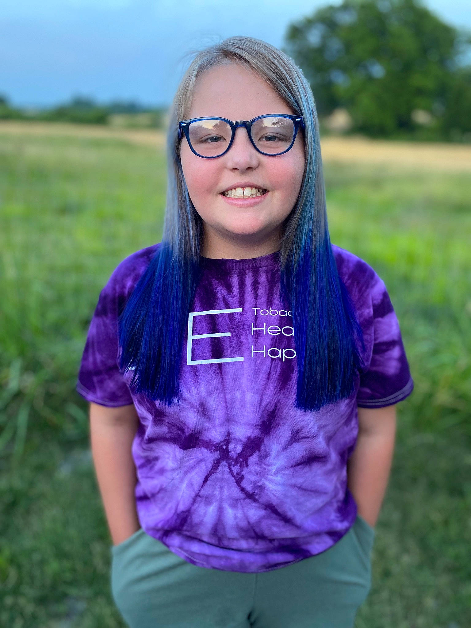 Maggie is registered to the contest to win money with this photo: electric_blue, eye, eyewear, flash_photography, gesture, grass, grassland, happy, head, iris, joy, lip, long_hair, meadow, neck, person, plant, purple, sky, sleeve