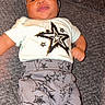 Jeremiah is registered to the contest to win money with this photo: baby, infant, smiling, lying_down, clothing, pants, headband, stars, pattern, soft_surface, cozy, cute, child, person, indoors, portrait, happy, toddler, fabric, casual