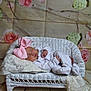 baby, sleeping, pink_bow, white_clothing, wicker_couch, lace, floral_backdrop, cute, newborn, soft, portrait, indoor, peaceful, child, infant, resting, decor, cozy, headwear, small