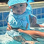 baby, child, water, pool, swimming_pool, hat, striped_clothing, sun_hat, blue, white, hands, reflection, outdoor, summer, infant, cute, person, skin, water_surface, holding