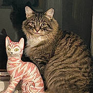 Stripy Cat is registered to the contest to win money with this photo: cat, tabby, ceramic_cat, statue, windowsill, indoor, pet, feline, striped, fur, animal, portrait, cute, curious, sitting, decor, shadow, closeup, domestic_cat, eyes