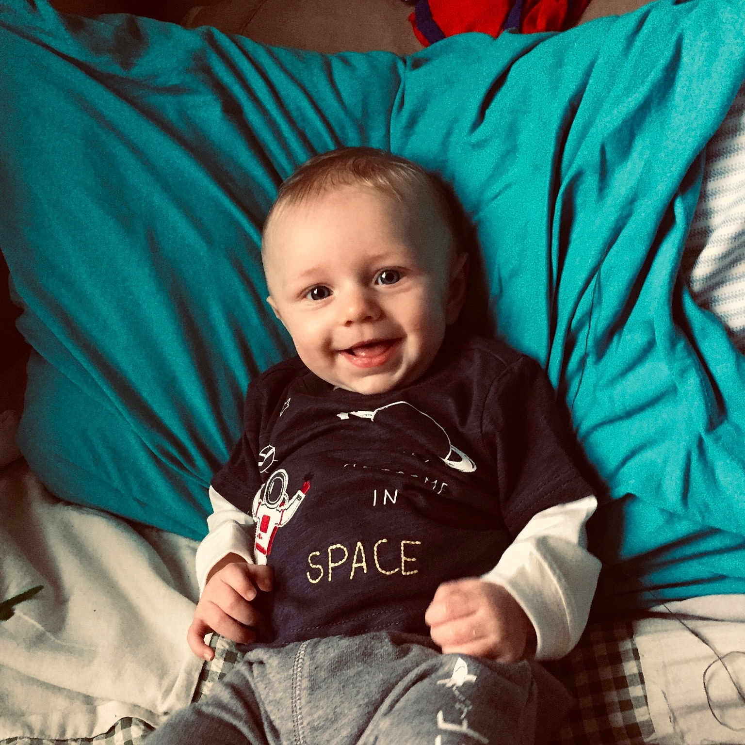 Foster is registered to the contest to win money with this photo: baby, blue, cheek, child, cool, electronic_device, eye, face, furniture, happy, head, jeans, leg, people, person, play, sitting, skin, smile, t_shirt