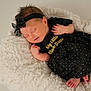 newborn, baby, sleeping, black_dress, headband, bow, blanket, soft_texture, infant, cute, peaceful, tiny_feet, clothing, portrait, indoors, resting, adorable, child, toddler, fashion