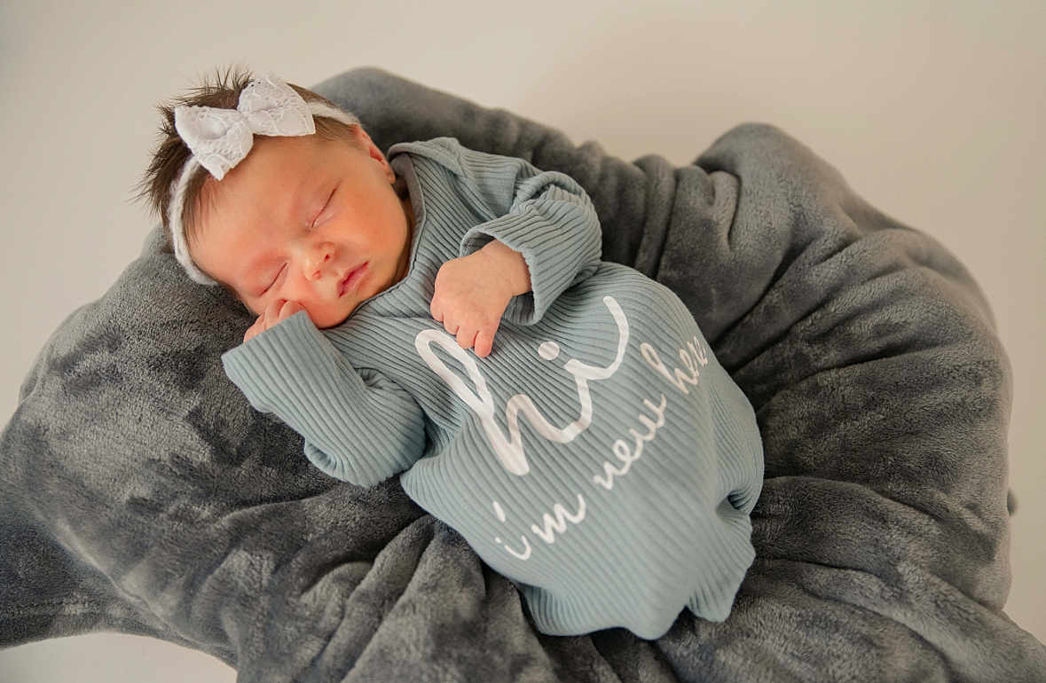 Koda joined the competition — help win amazing prizes! newborn, baby, sleeping, blanket, headband, bow, clothing, cozy, cute, infant, soft, portrait, resting, child, peaceful, rippled_fabric, grey, white, text_on_clothing, indoors