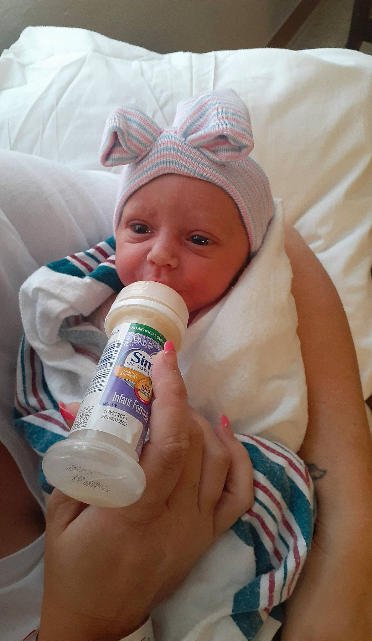 Sabrina is registered to the contest to win money with this photo: baby, baby_bottle, bottle, comfort, drink, drinking, drinkware, eyelash, face, finger, fluid, gesture, hand, happy, headwear, health_care, nose, person, plastic_bottle, skin