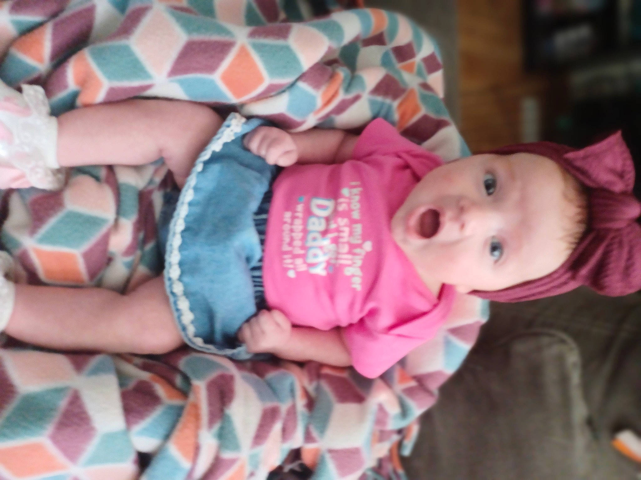 Rhea is registered to the contest to win money with this photo: arm, baby, baby_carriage, baby_products, baby_toddler_clothing, beauty, cheek, child, comfort, face, hand, human_body, pattern, person, pink, product, room, sitting, skin, surprise