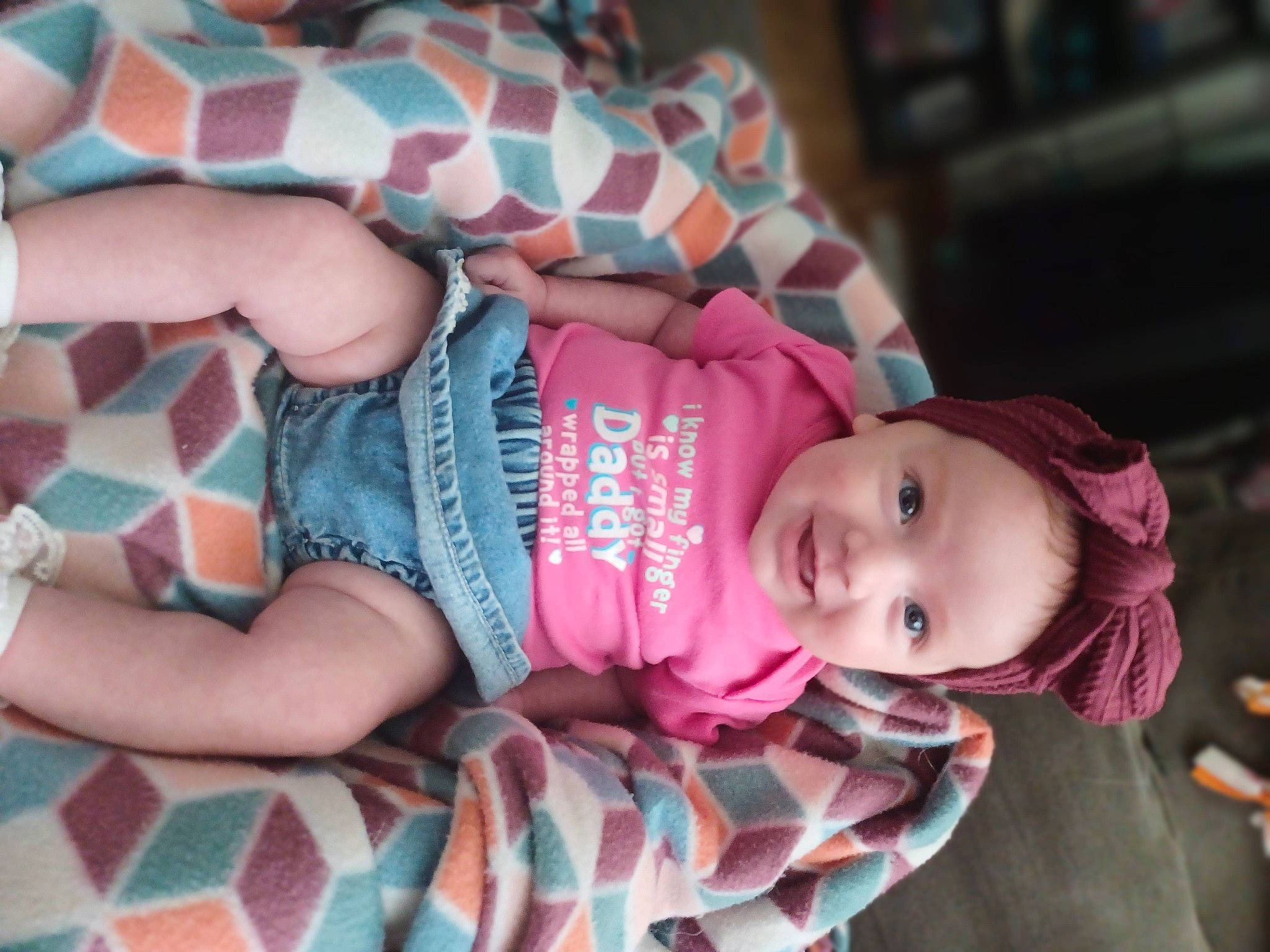 Rhea is registered to the contest to win money with this photo: baby, baby_products, baby_toddler_clothing, cheek, child, comfort, dress, finger, headwear, human_body, mouth, nail, pattern, person, pink, sitting, skin, sleeve, smile, textile