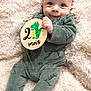 baby, infant, child, portrait, blanket, fur_texture, onesie, green_clothing, dinosaur_sign, two_months, month_marker, hand, fingers, big_eyes, smile, cozy, soft_texture, lying_down, closeup, cute