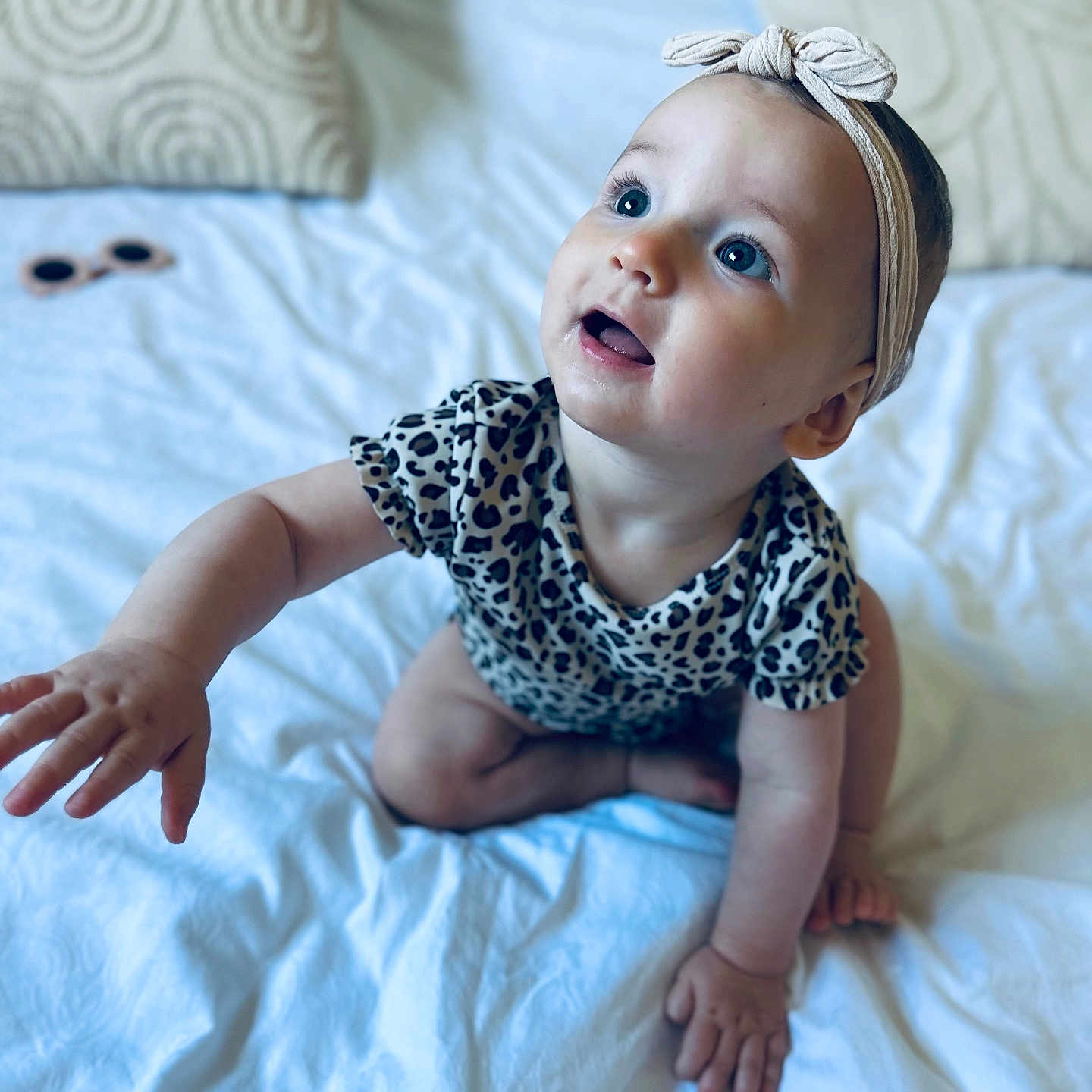 Eléa a rejoint le concours — aidez-le/la à gagner de superbes lots ! baby, bed, blue_eyes, child, closeup, comfortable, crawling, curious, cute, happy, headband, indoors, infant, patterned_clothing, pillows, portrait, reaching_hand, soft_lighting, sunglasses, young_child