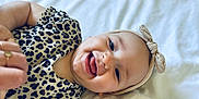 Eléa participe au concours pour gagner de l'argent avec cette photo : adult_hand, apparel, baby, bow, child, closeup, cute, hand, happy, headband, infant, leopard_print, lying_down, person, playful, portrait, skin, smiling, tongue_out, white_background