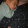 baby, sleeping, child, person, face, clothing, star_pattern, shirt, cuddle, rest, comfort, indoor, closeup, skin, head, arm, young, peaceful, human, portrait