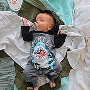Kassian joined the competition — help win amazing prizes! baby, infant, pacifier, clothing, onesie, shark_design, blanket, quilt, remote_control, bed, sleepwear, foot, hand, lying_down, indoors, comfort, soft_texture, child, cute, resting