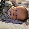 Kassian is registered to the contest to win money with this photo: baby, sleeping, pacifier, blanket, soft_clothing, infant, cozy, indoors, nap, newborn, head, face, peaceful, child, resting, cute, warm_light, closeup, portrait, comfort