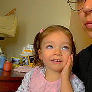 Leysa participe au concours pour gagner de l'argent avec cette photo : child, toddler, girl, pigtails, pink_clothing, floral_pattern, hand_on_cheek, thoughtful, indoor, table, adult, glasses, face, person, portrait, hair_clip, furniture, expression, curly_hair, casual_wear