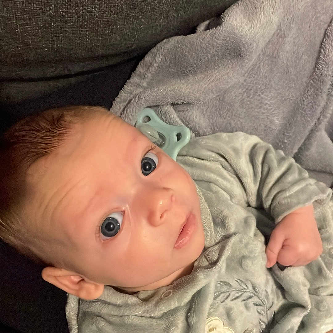 Livaï a rejoint le concours — aidez-le/la à gagner de superbes lots ! baby, blanket, child, clothing, comfort, couch, cozy, cute, expression, face, hand, head, indoors, infant, pacifier, portrait, sitting, soft_texture, wide_eyes, young