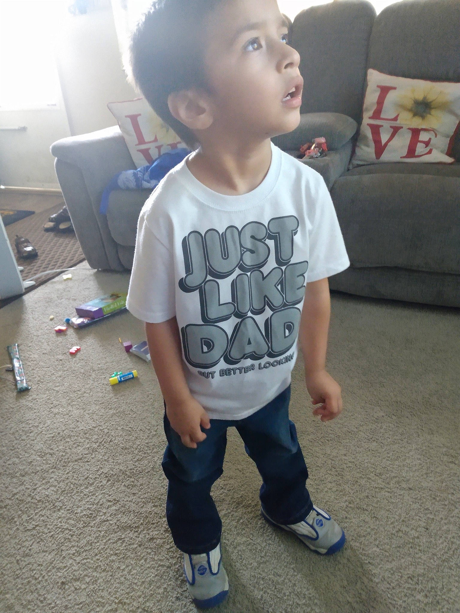 Connor is registered to the contest to win money with this photo: baby_toddler_clothing, child, couch, face, floor, flooring, hair, hairstyle, happy, head, joint, knee, neck, person, shoe, shorts, shoulder, sleeve, sneakers, t_shirt