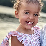 Lina a rejoint le concours — aidez-le/la à gagner de superbes lots ! child, toddler, smiling, portrait, outdoor, water, dress, pink, white, stripes, curly_hair, happy, face, person, sunlight, nature, ruffles, earrings, closeup, summer