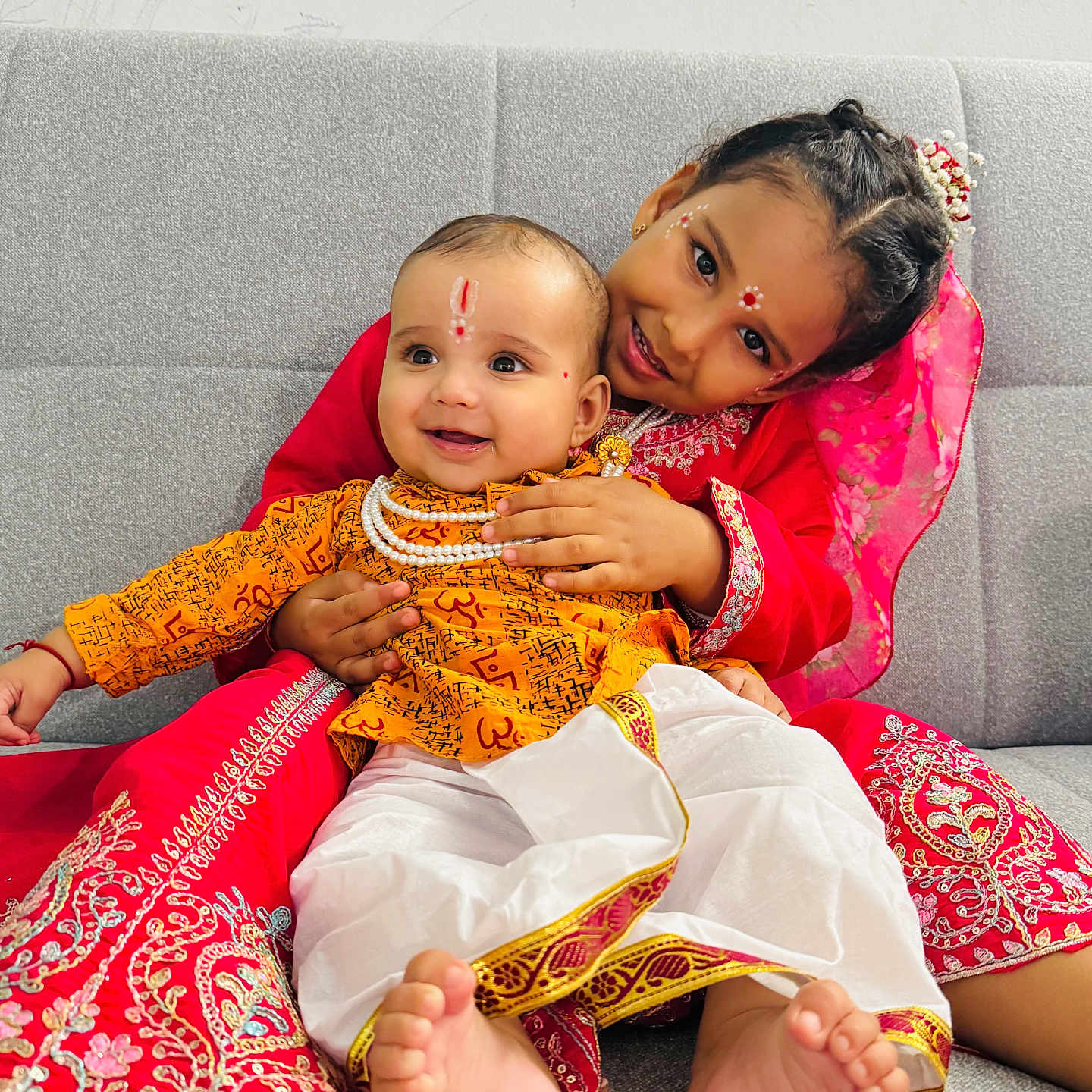 Divit is registered to the contest to win money with this photo: baby, barefoot, celebration, child, couch, cultural, cute, embrace, face_paint, family, happy, indoor, joy, portrait, red_dress, sitting, smiling, toddler, traditional_clothing, yellow_outfit