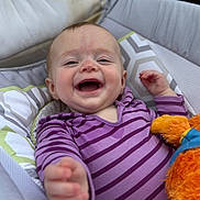 Annabella is registered to the contest to win money with this photo: baby, smiling, purple_striped_clothing, plush_toy, infant, cushioned_seat, happy, reaching_hand, face, person, portrait, indoor, child, cute, comfort, soft_toys, playful, closeup, head, young_child