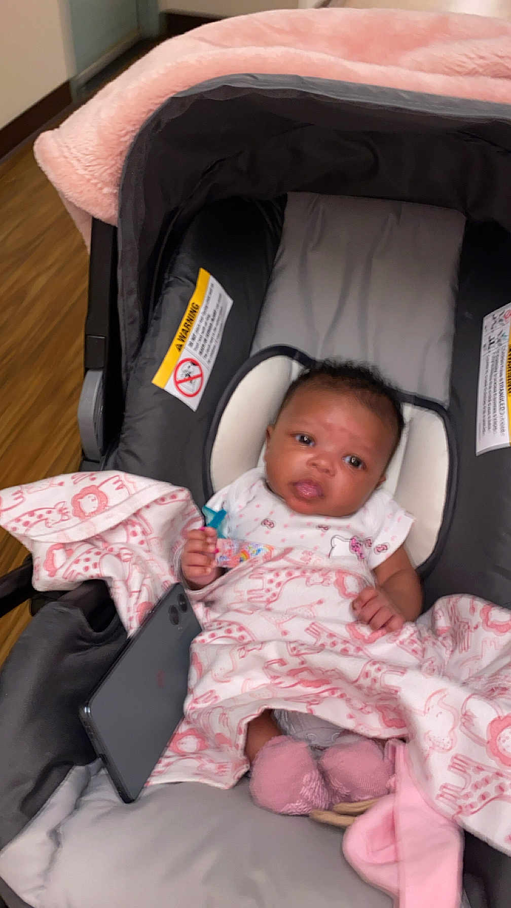 Saleen joined the competition — help win amazing prizes! baby, infant, car_seat, blanket, pink, pacifier, pacifier_clip, smartphone, socks, face, eyes, hands, clothing, head_support, wood_floor, indoor, portrait, newborn, cute, cozy