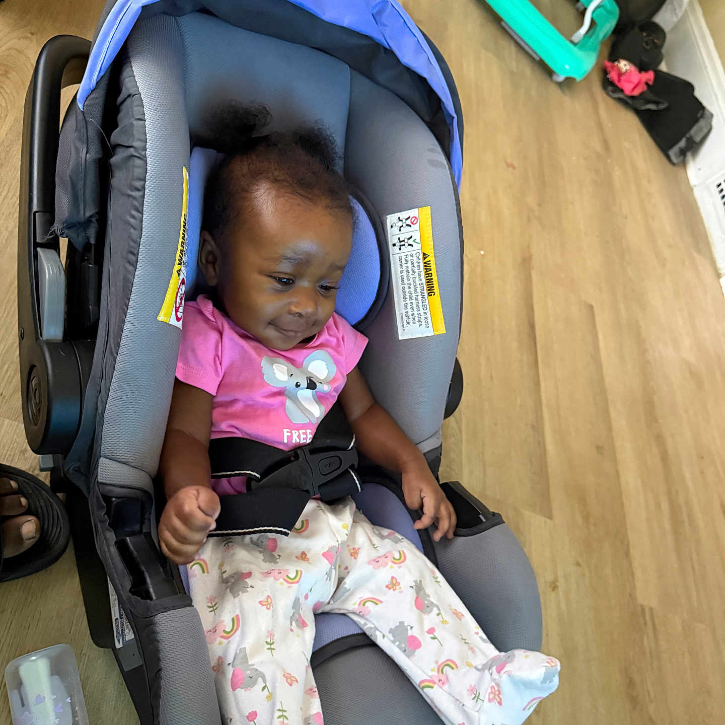 Mickiyah is registered to the contest to win money with this photo: baby, car_seat, infant, pink_shirt, pajamas, baby_bottle, wooden_floor, indoor, child, hair_puffs, clothing, seat_belt, toy, floor, person, baby_gear, casual, cute, relaxed, smiling