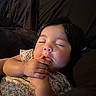 Valerie is registered to the contest to win money with this photo: toddler, child, sleeping, hand, finger, face, floral_clothing, indoors, portrait, peaceful, cute, baby, skin, dark_hair, rest, comfort, soft_light, candid, closeup, person