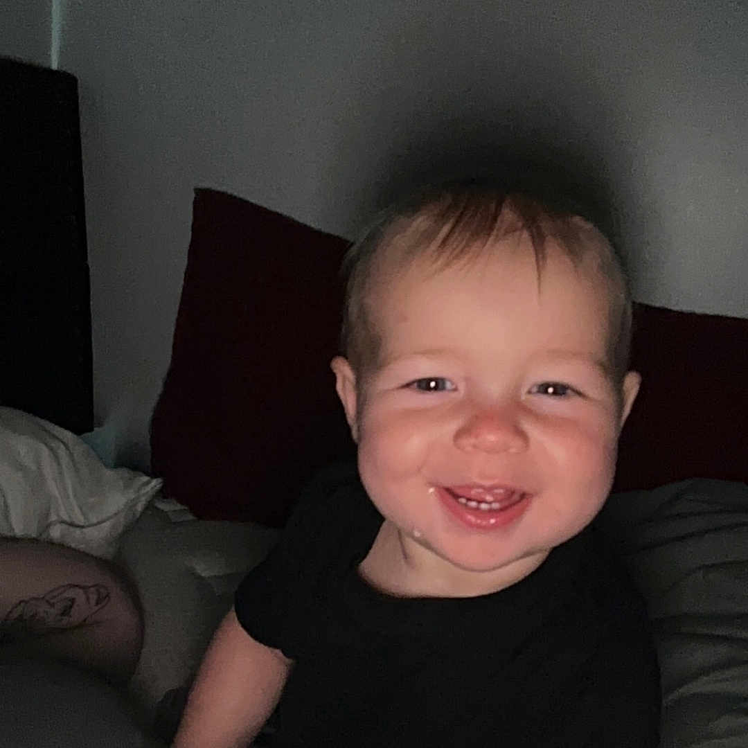 Ryder is registered to the contest to win money with this photo: baby, bed, bedroom, bodypart, clothing, couch, cushion, face, furniture, happy, head, homedecor, indoors, laughing, person, photography, portrait, room, smile, t_shirt