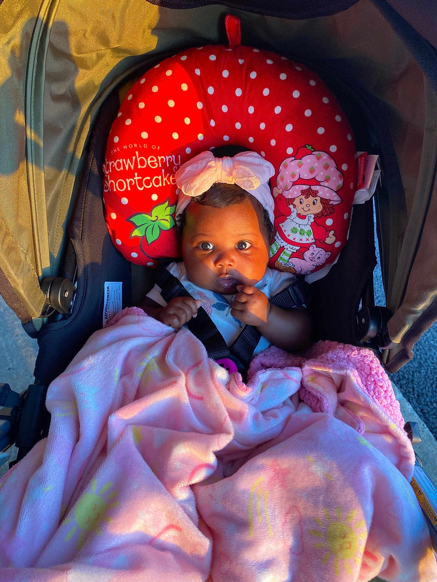 Kyomi joined the competition — help win amazing prizes! baby, blanket, stroller, child, pink, red, neck_pillow, strawberry_shortcake, face, headband, curious, sunlight, seatbelt, cute, infant, indoor, clothing, person, portrait, comfort