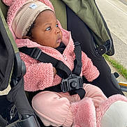 Kyomi is registered to the contest to win money with this photo: baby, child, stroller, pink_clothing, hat, booties, jacket, straps, outdoor, curious, face, person, seat, infant, cute, warm_clothing, side_profile, black_hair, bundle, transportation