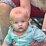 adult, baby, blue_eyes, blurred_background, child, closeup, curious, expression, face, gentle, hands, holding, infant, mint_green_shirt, outdoor, patterned_shirt, person, portrait, short_hair, skin