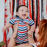 Jonathan joined the competition — help win amazing prizes! baby, child, smiling, happy, striped_clothing, colorful, tattoo, hands, nails, adult, holding, indoor, decor, plant, portrait, face, cute, joy, person, background