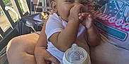 Meilani joined the competition — help win amazing prizes! baby, child, person, adult, hands, bottle, thumb_sucking, curly_hair, earrings, clothing, porch, sunlight, shadow, chair, lap, nail_polish, relaxing, casual, home, outdoor
