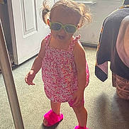 Amira is registered to the contest to win money with this photo: carpet, child, cute, door, dress, fashion, footwear, hair, happy, indoors, person, pigtails, pink_slippers, playful, room, smiling, standing, sunglasses, sunlight, toddler