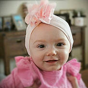 Iris joined the competition — help win amazing prizes! baby, baby_girl, background_blur, child, closeup, cute, face, flower, furniture, happy, headband, home_interior, indoor, infant, person, pink_clothing, portrait, smile, soft_lighting, young_child