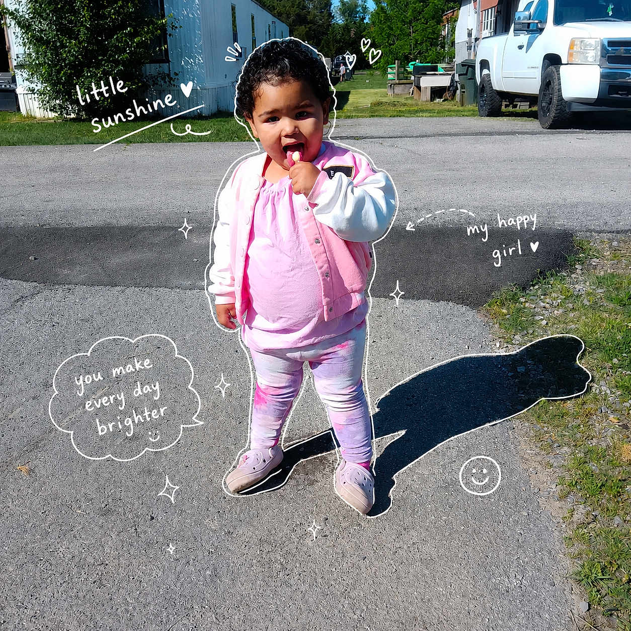 Nova is registered to the contest to win money with this photo: toddler, child, pink_clothing, lollipop, outdoor, sunny_day, doodle_art, text_overlay, shadow, driveway, grass, building, vehicle, smiling, happy, person, casual_wear, curly_hair, footwear, playful