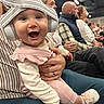 Rebekah joined the competition — help win amazing prizes! baby, headphones, pink_outfit, smiling, indoor, crowd, people, seated, adult, child, joyful, casual_clothing, footwear, hand, face, event, happy, closeup, person, holding