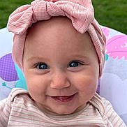 Rebekah is registered to the contest to win money with this photo: baby, child, smiling, headband, bow, pink, face, blue_eyes, cute, infant, outdoor, greenery, striped_clothing, portrait, happy, closeup, person, toddler, headwear, cheeky