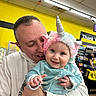 baby, man, unicorn_hat, smile, happy, child, person, indoor, store, shelf, clothing, hoodie, colorful, portrait, cute, holding, bright, background, retail, shopping