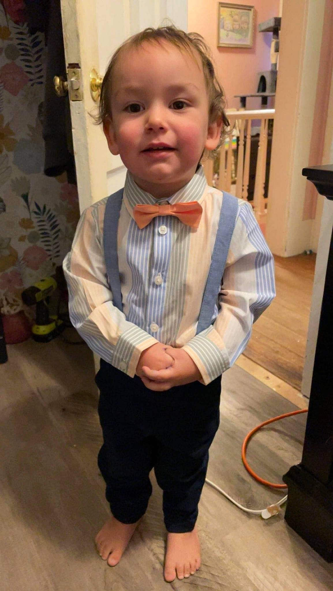 Adonis is registered to the contest to win money with this photo: baby, blond, child, curtain, dress_shirt, eye, flooring, formal_wear, fun, gesture, leg, nose, person, shorts, sitting, sleeve, t_shirt, thumb, tie, toddler