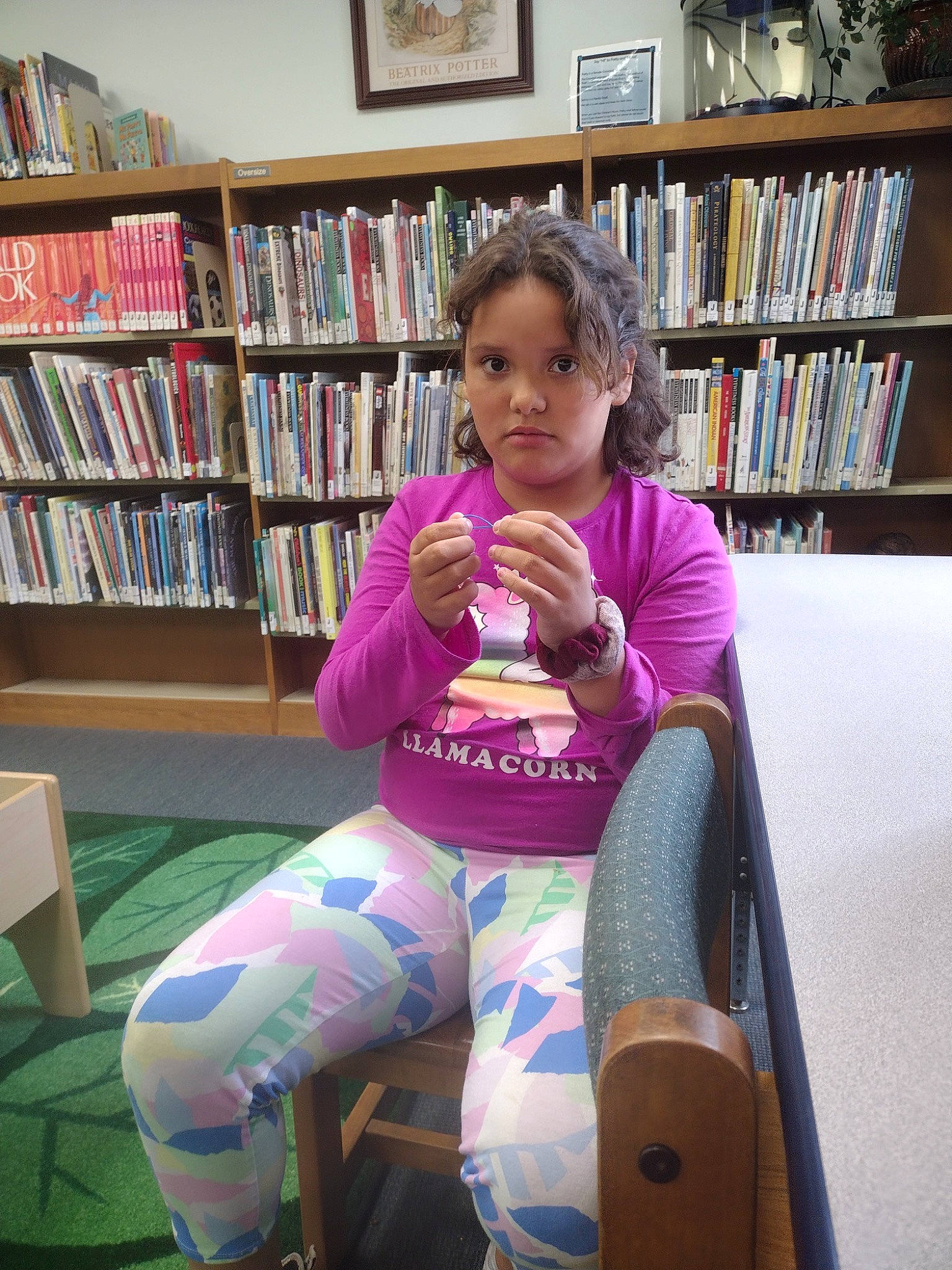 Alisianna is registered to the contest to win money with this photo: book, bookcase, chair, child, comfort, flooring, fun, furniture, human_leg, joint, knee, lap, leisure, magenta, person, picture_frame, publication, shelf, shelving, sitting