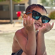 Kanaloa is registered to the contest to win money with this photo: child, boy, smile, sunglasses, water, wet_skin, summer, outdoor, poolside, shorts, happy, cute, reflection, sunlight, playful, skin, portrait, sitting, casual, daylight
