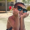child, boy, smile, sunglasses, water, wet_skin, summer, outdoor, poolside, shorts, happy, cute, reflection, sunlight, playful, skin, portrait, sitting, casual, daylight
