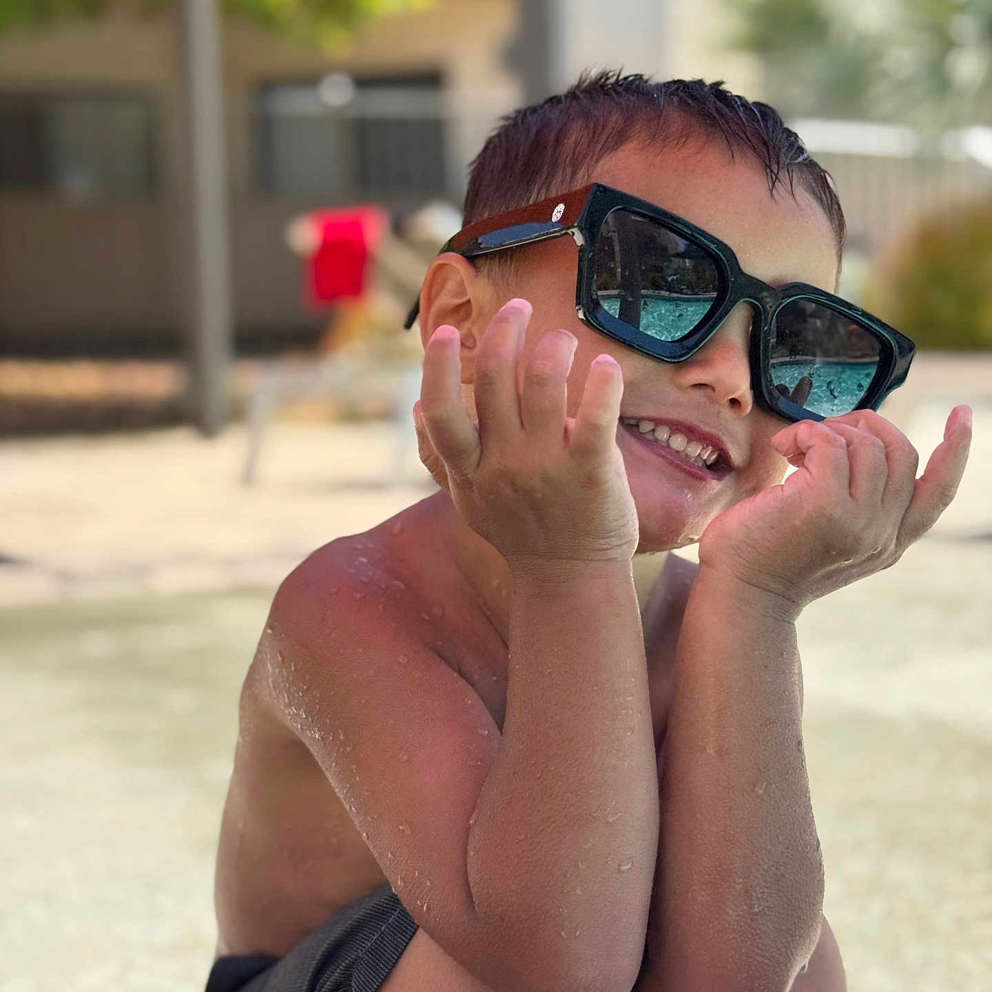 Kanaloa is registered to the contest to win money with this photo: child, boy, smile, sunglasses, water, wet_skin, summer, outdoor, poolside, shorts, happy, cute, reflection, sunlight, playful, skin, portrait, sitting, casual, daylight