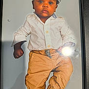 Kaeson is registered to the contest to win money with this photo: child, toddler, portrait, curly_hair, white_shirt, mustard_pants, standing, serious_expression, indoor, light_glare, cute, young_child, fashion, person, photograph, studio, small_child, casual_clothing, cute_face, background