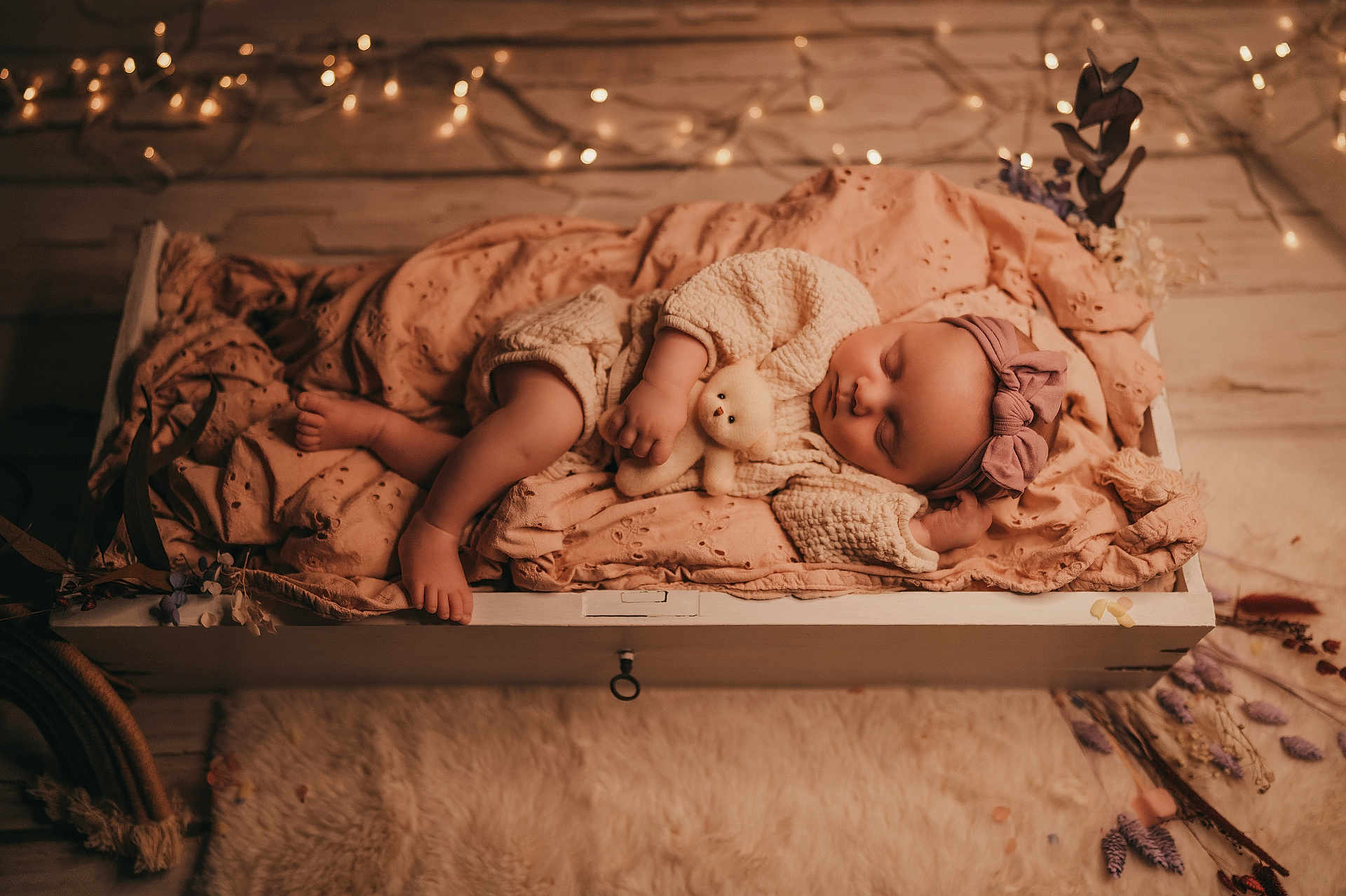 Mahyna participe au concours pour gagner de l'argent avec cette photo : baby, sleeping, teddy_bear, blanket, headband, knitwear, cozy, wooden_drawer, fairy_lights, soft_lighting, indoor, decor, floor, rug, flowers, peaceful, infant, portrait, cute, resting