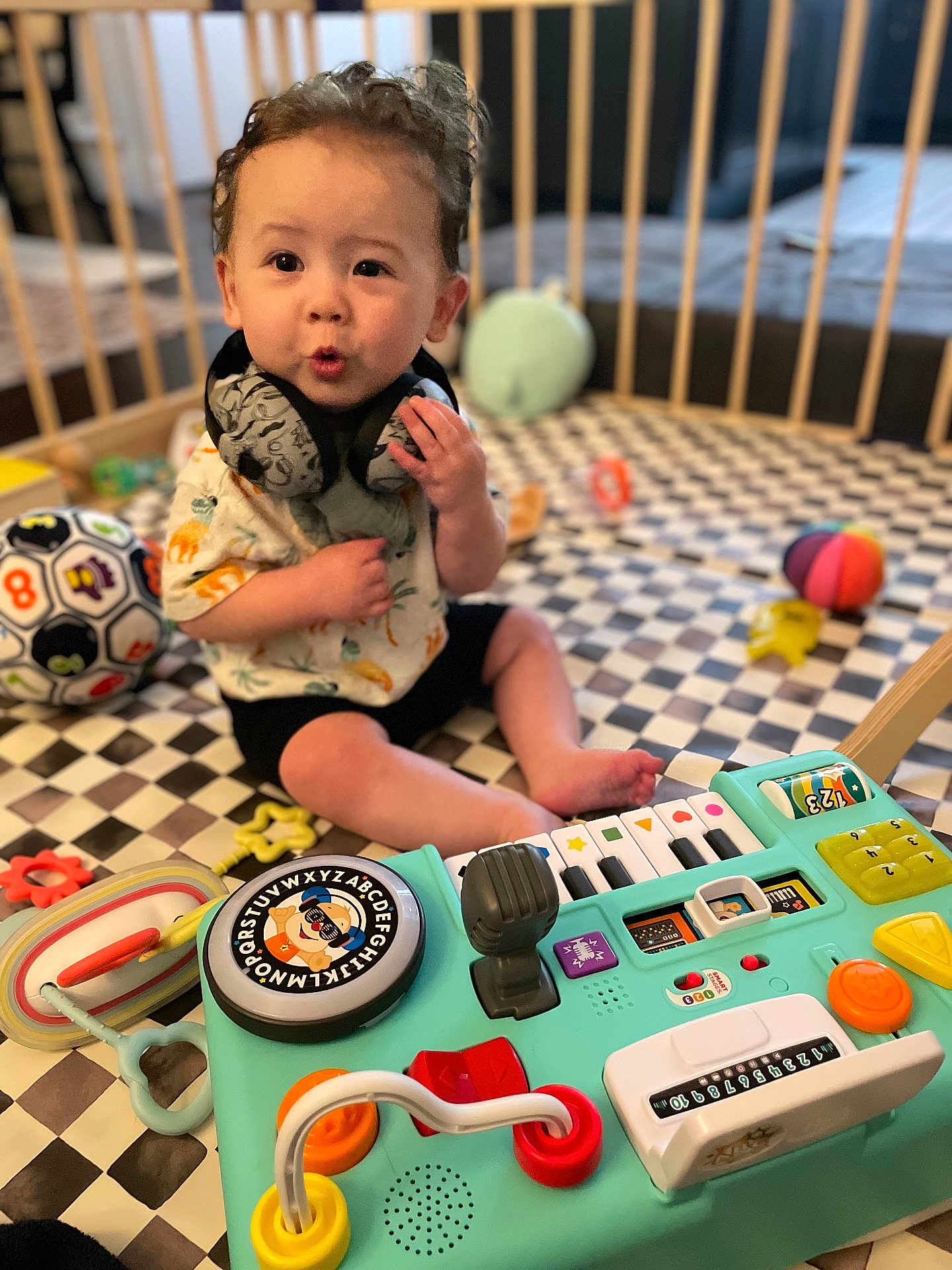 Miles joined the competition — help win amazing prizes! toddler, child, toy, playpen, activity_center, colorful, indoor, curly_hair, expression, playful, sitting, floor_mat, soccer_ball, infant, cute, baby, engaged, hand, clothing, headphones