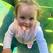Charlotte joined the competition — help win amazing prizes! blue_eyes, casual_clothing, child, curly_hair, cute, green_surface, hand, outdoor, person, pigtail, pink_vest, play, playground, portrait, shadow, smile, sunlight, toddler, white_shirt, young_child