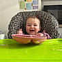 baby, high_chair, leopard_print, pink_plate, green_tray, messy_face, kitchen, food_chart, smiling, child, feeding, cute, infant, happy, table, wall_chart, utensils, domestic, portrait, indoor