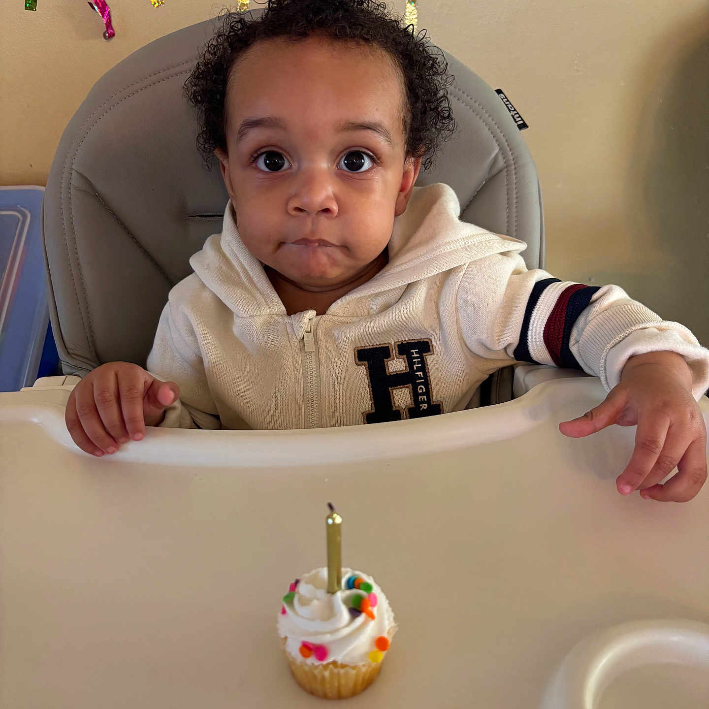 Mayson joined the competition — help win amazing prizes! birthday_candle, celebration, child, colorful_streamers, cupcake, curly_hair, cute, expression, face, festive, food, hands, high_chair, indoor, party_decorations, person, table, toddler, white_jacket, young_child
